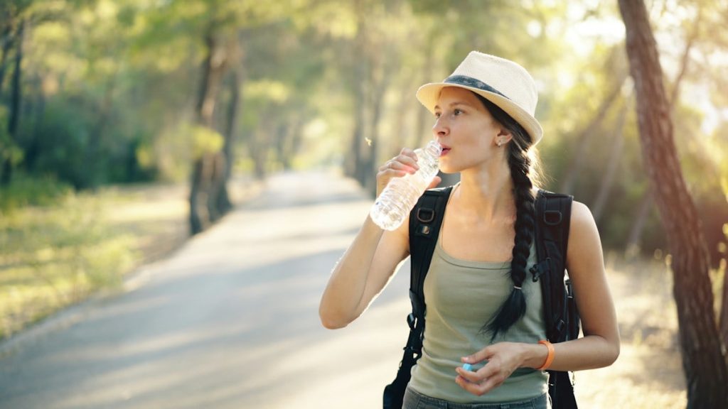 a woman in a hat drinking water from a bottle